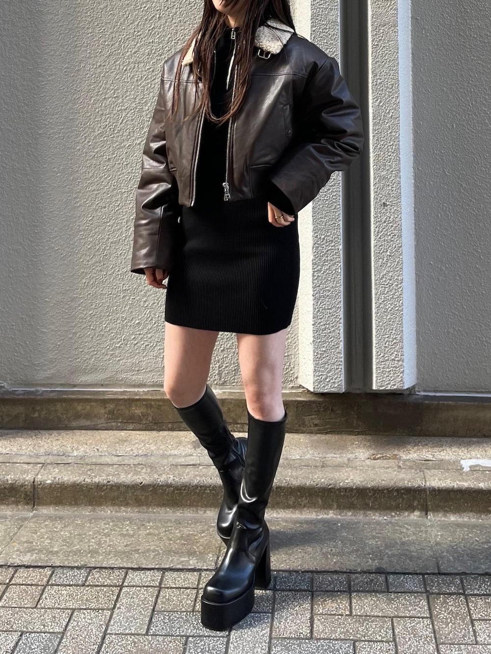 ブラウン系のブルゾン、ブラック系のワンピース、ブラック系のブーツを着用したレディースの秋コーディネートの3枚目の写真