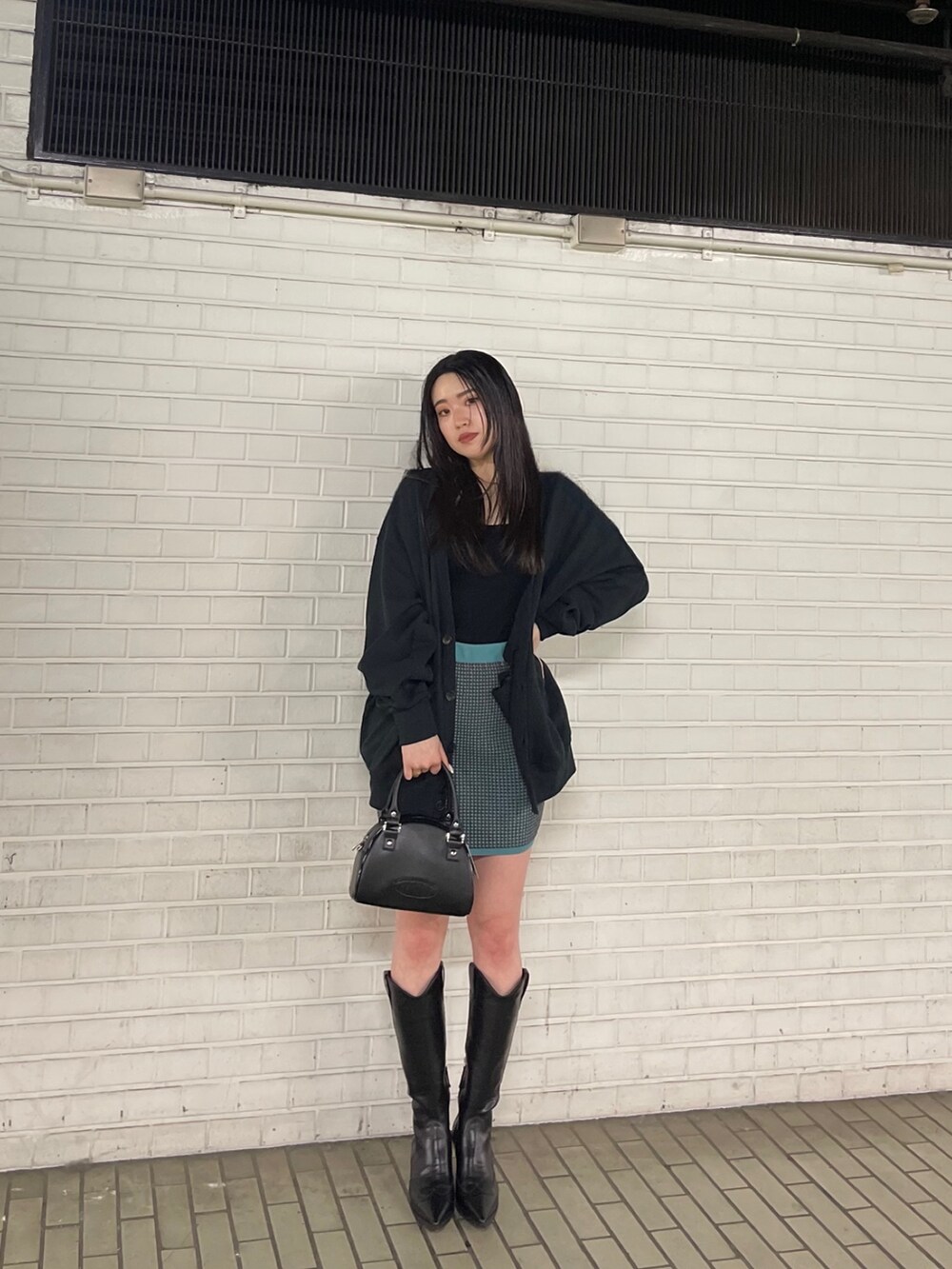 ブラック系のブーツ、ブルー系のスカート、ブラック系のカーディガン/ボレロを着用したレディースの春コーディネートの4枚目の写真