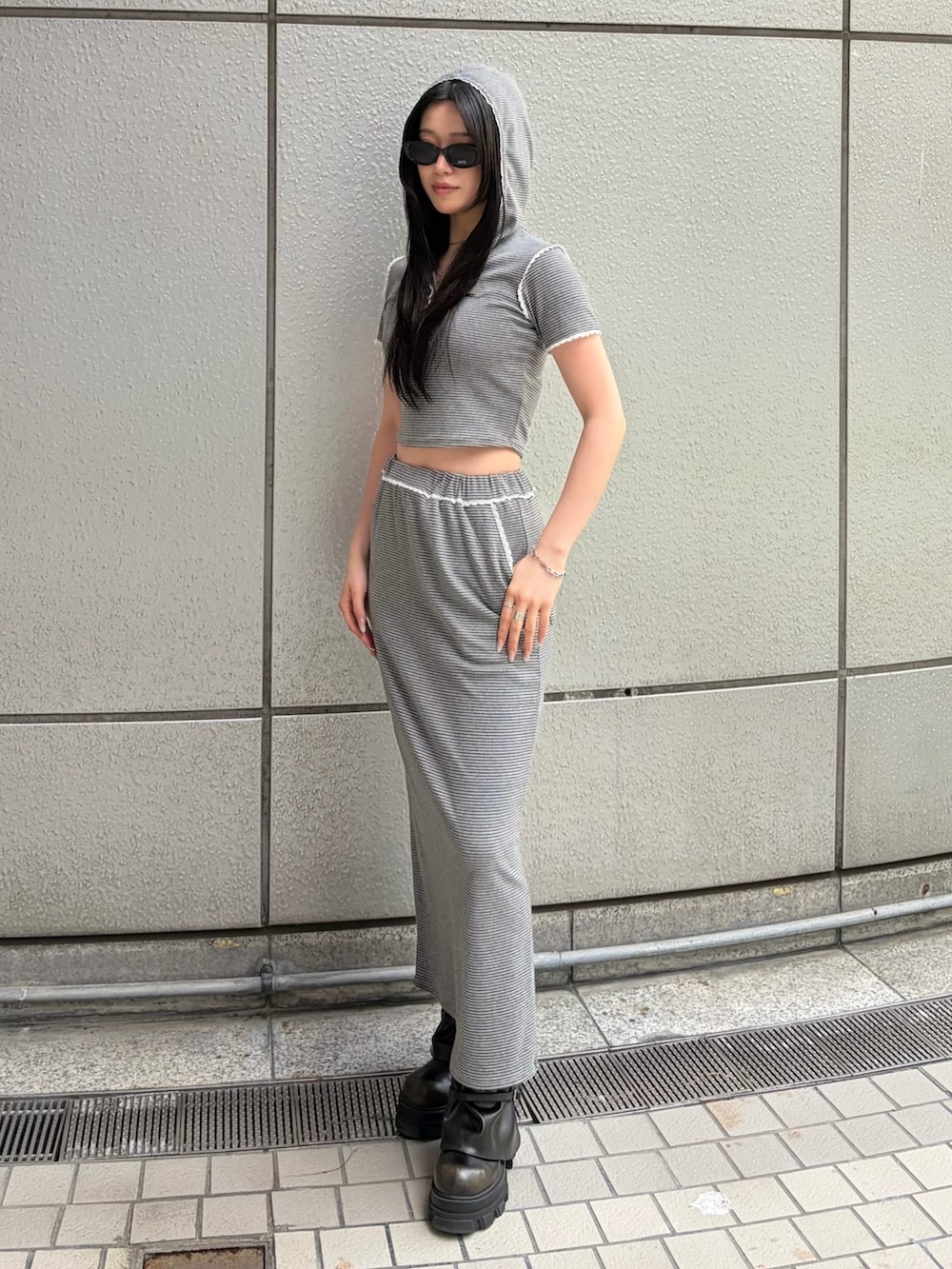 グレー系のスカート、グレー系のTシャツ/カットソー、ブラック系のブーツを着用したレディースの春コーディネートの3枚目の写真