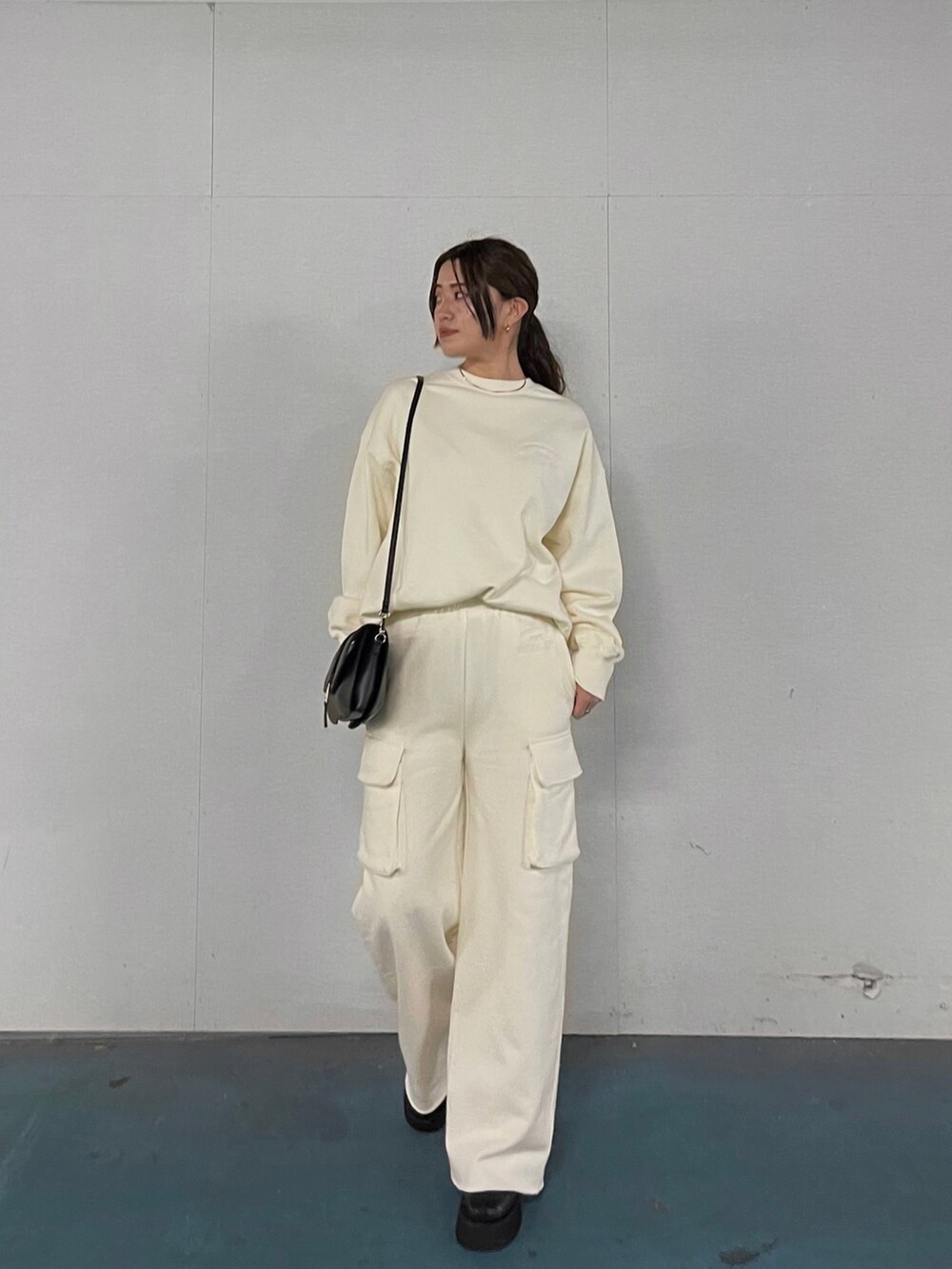 ホワイト系のTシャツ/カットソー、ホワイト系のスウェットパンツ、ブラック系のブーツを着用したレディースの秋コーディネートの2枚目の写真