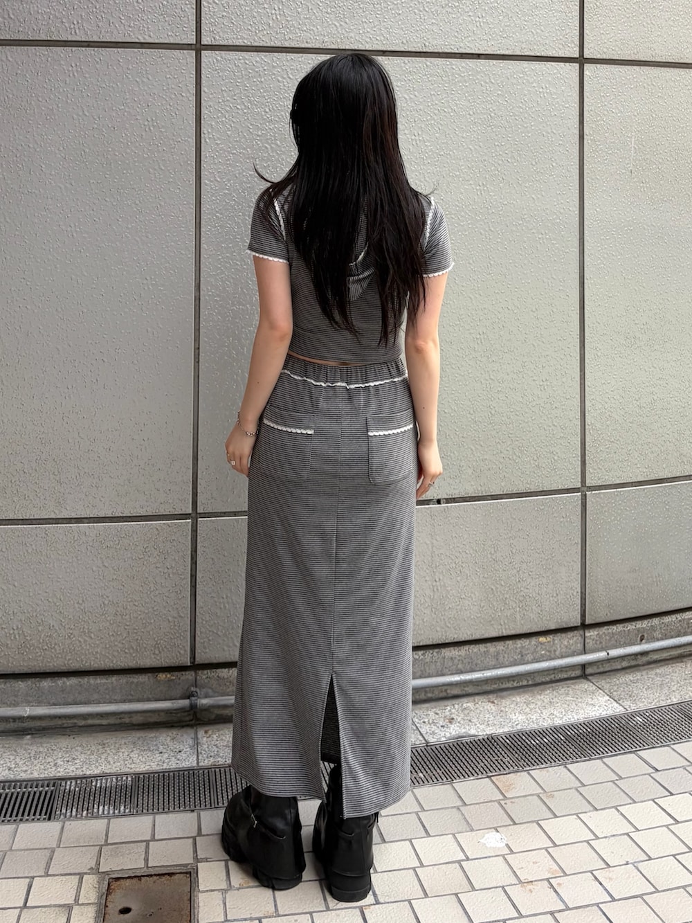 グレー系のスカート、グレー系のTシャツ/カットソー、ブラック系のブーツを着用したレディースの春コーディネートの6枚目の写真