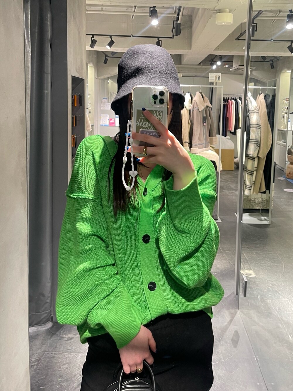 グリーン系のカーディガン/ボレロ、ブラック系のスカート、ブラック系のブーツを着用したレディースの冬コーディネートの2枚目の写真