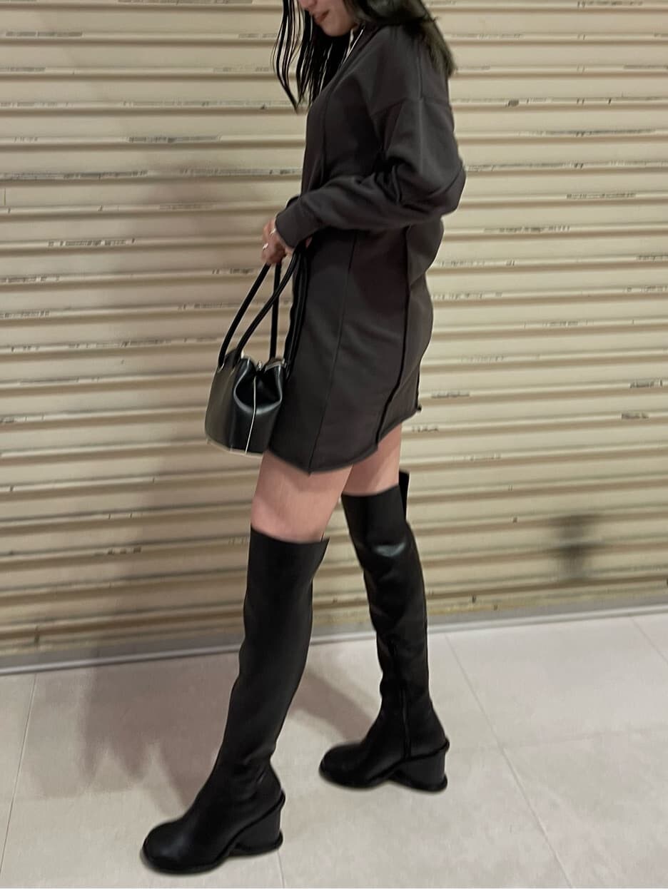 グレー系のワンピース、ブラック系のブーツ、ブラック系のハンドバッグを着用したレディースの秋コーディネートの3枚目の写真