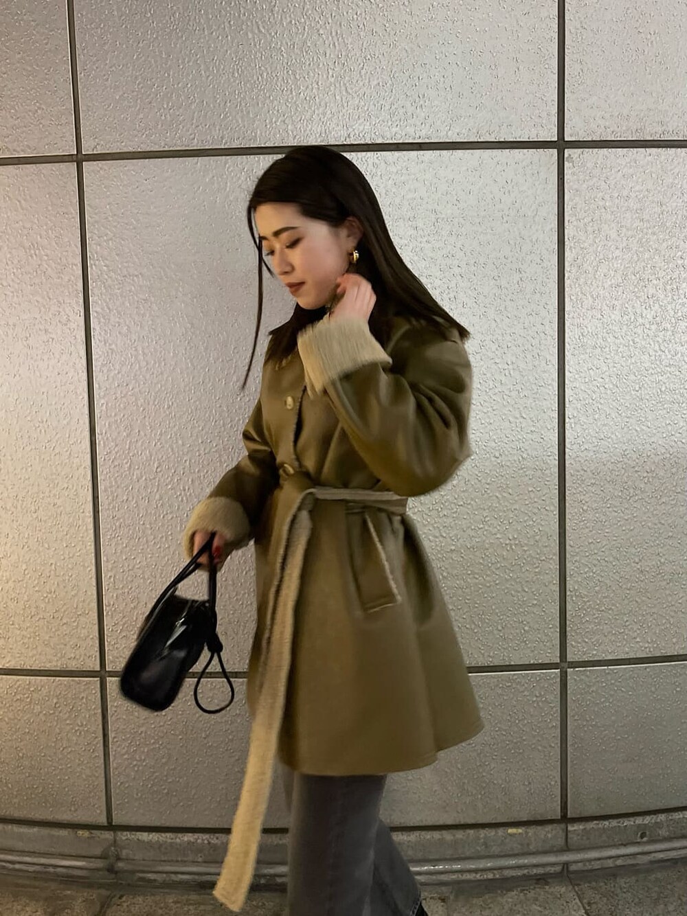 ブラック系のハンドバッグ、ベージュ系のムートンコート、ホワイト系のニット/セーターを着用したレディースの冬コーディネートの3枚目の写真