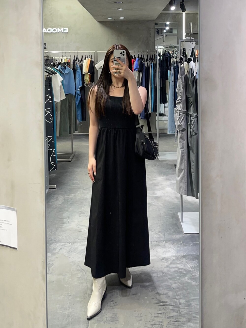 ブラック系のワンピース、ホワイト系のブーツ、ブラック系のハンドバッグを着用したレディースの夏コーディネートの2枚目の写真