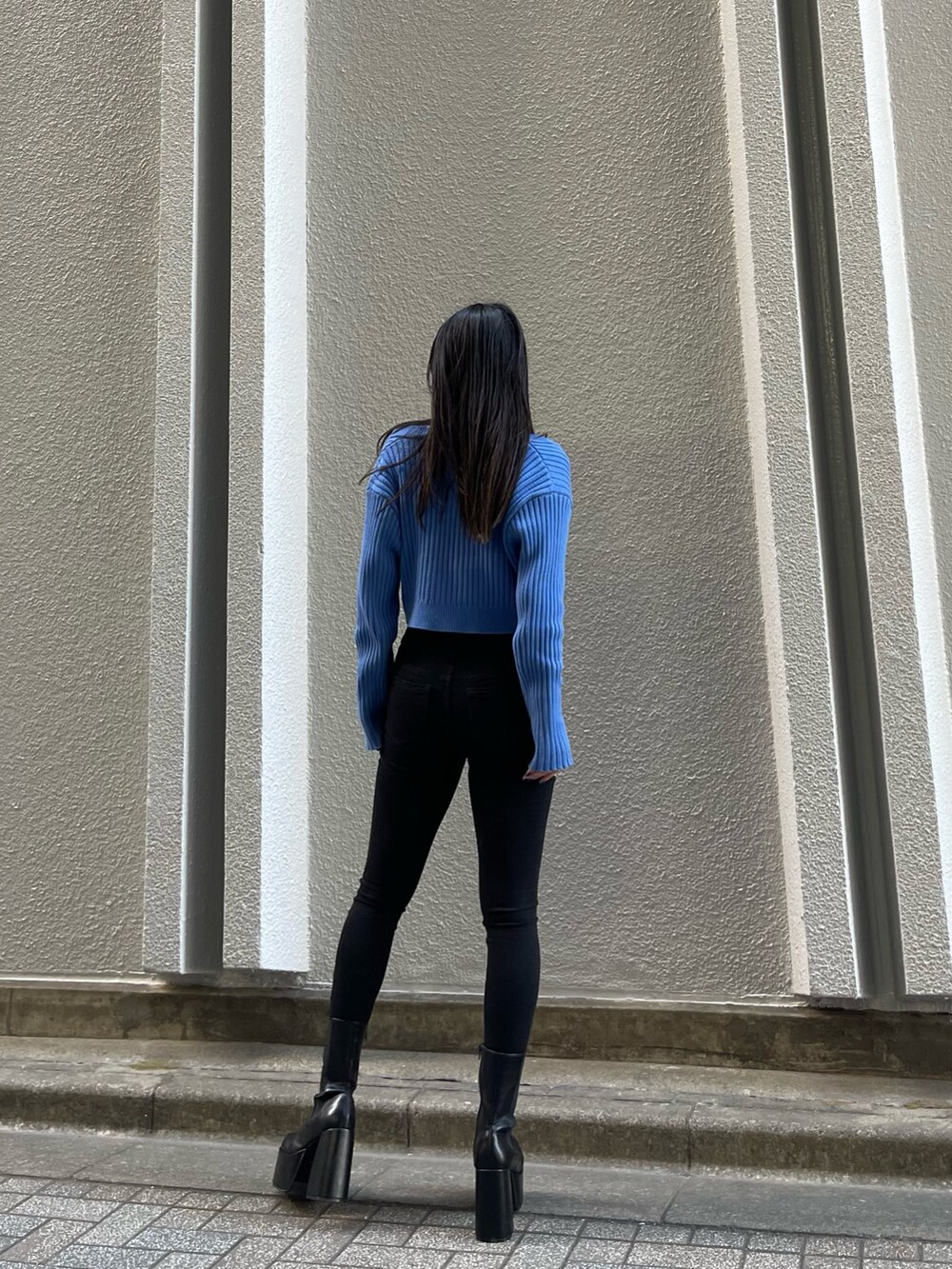 ブラック系のデニムパンツ、ブルー系のカーディガン/ボレロ、ブラック系のブーツを着用したレディースの冬コーディネートの3枚目の写真