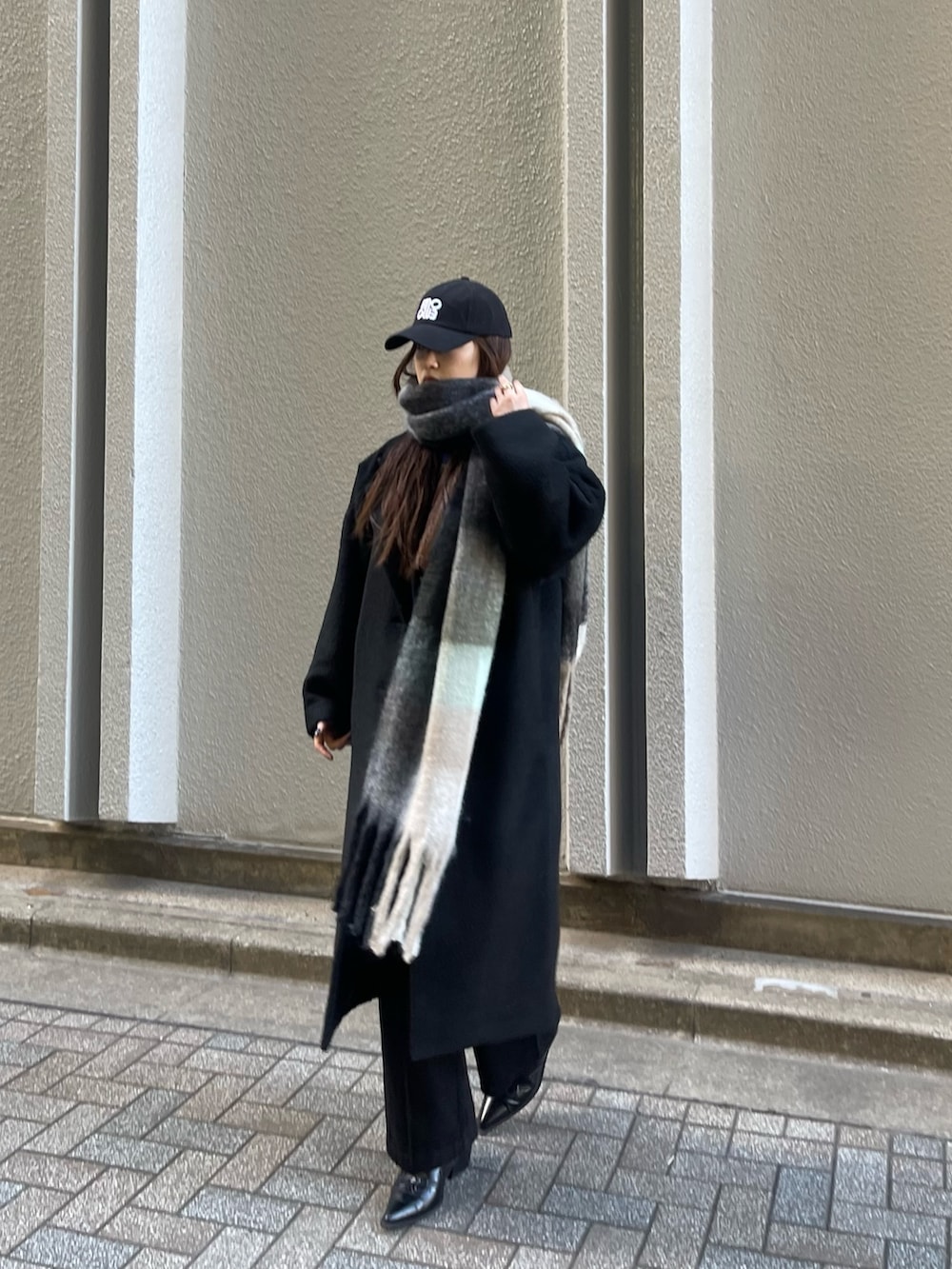 ブラック系のチェスターコート、ブラック系のデニムパンツ、ブラック系のマフラーを着用したレディースの冬コーディネートの4枚目の写真