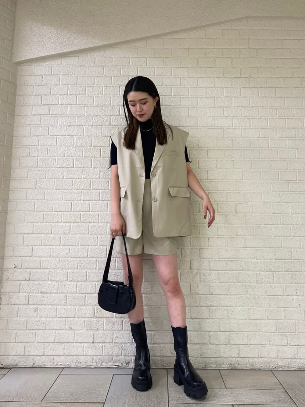 ベージュ系のベスト、ベージュ系のその他パンツ、ブラック系のブーツを着用したレディースの夏コーディネートの2枚目の写真