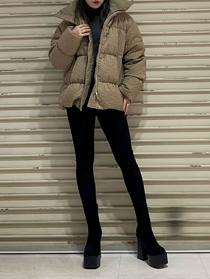 ブラック系のデニムパンツ、ブラック系のブーツ、ベージュ系のダウンジャケット/コートを着用したレディースの秋コーディネートの2枚目の写真