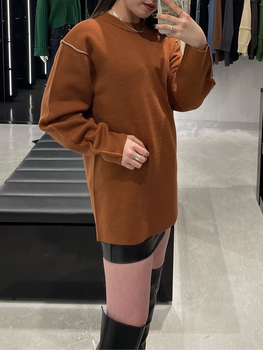 オレンジ系のニット/セーター、ブラック系のブーツを着用したレディースの秋コーディネートの4枚目の写真