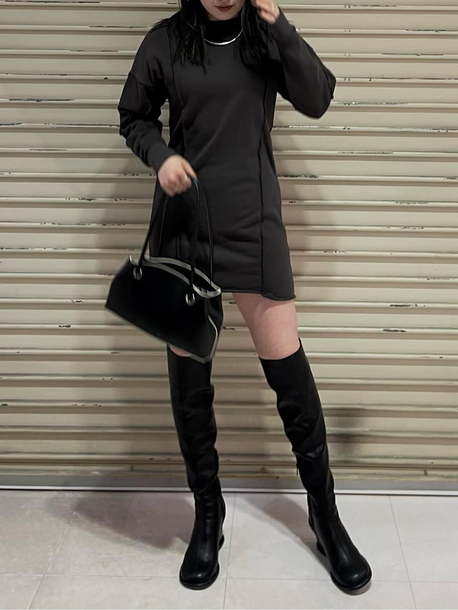 グレー系のワンピース、ブラック系のブーツ、ブラック系のハンドバッグを着用したレディースの秋コーディネートの2枚目の写真