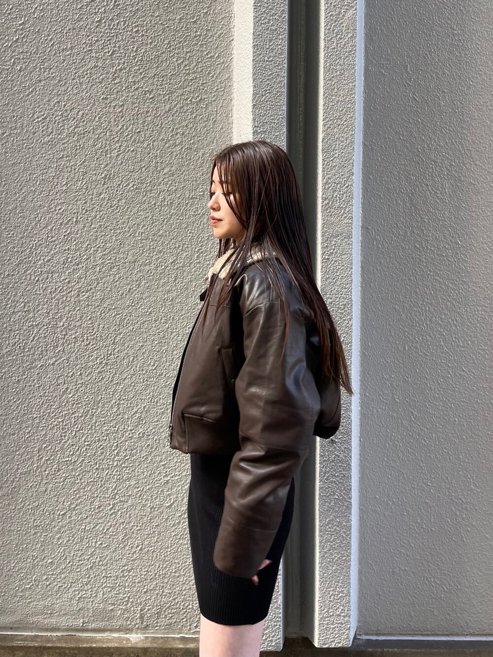 ブラウン系のブルゾン、ブラック系のワンピース、ブラック系のブーツを着用したレディースの秋コーディネートの4枚目の写真