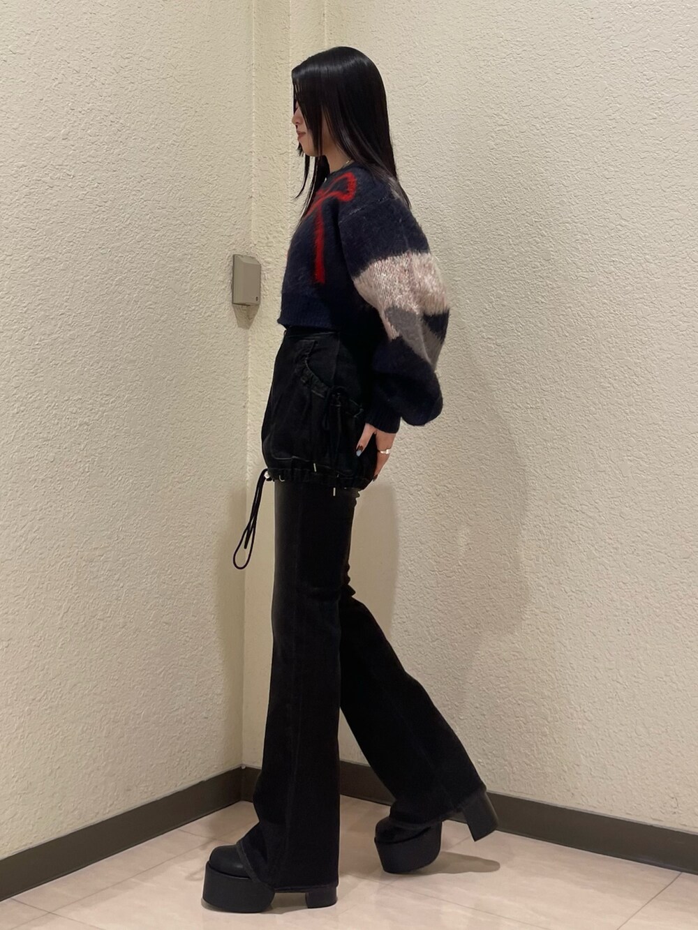 ブラック系のデニムパンツ、ブルー系のニット/セーター、ブラック系のブーツを着用したレディースの秋コーディネートの4枚目の写真