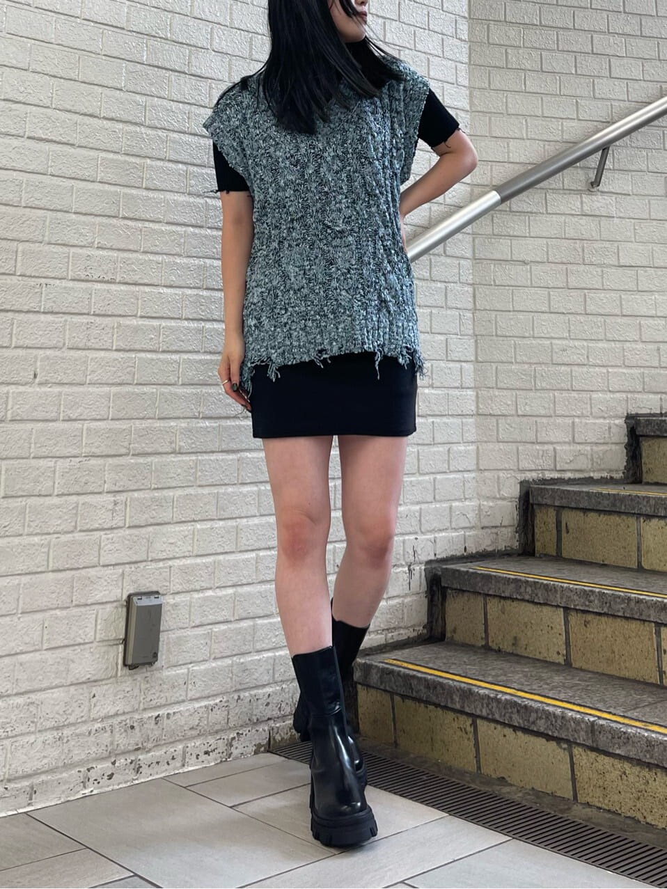 ブラック系のスカート、ブラック系のブーツ、ブラック系のニット/セーターを着用したレディースの夏コーディネートの2枚目の写真