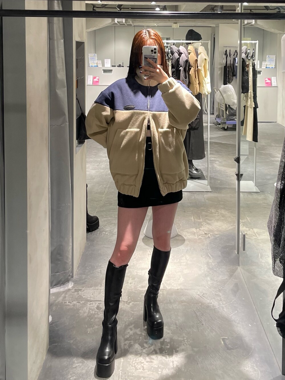 ブルー系のブルゾン、ブラック系のスカート、ブラック系のブーツを着用したレディースの秋コーディネートの6枚目の写真