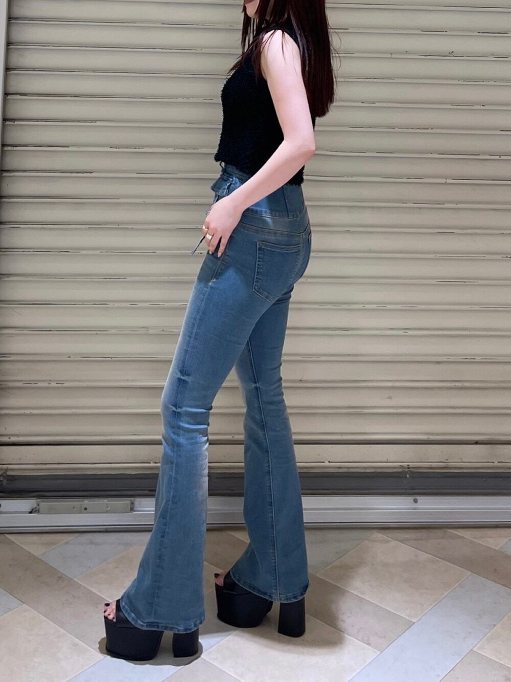 ブラック系のタンクトップ、ブルー系のデニムパンツ、ブラック系のサンダルを着用したレディースの夏コーディネートの4枚目の写真