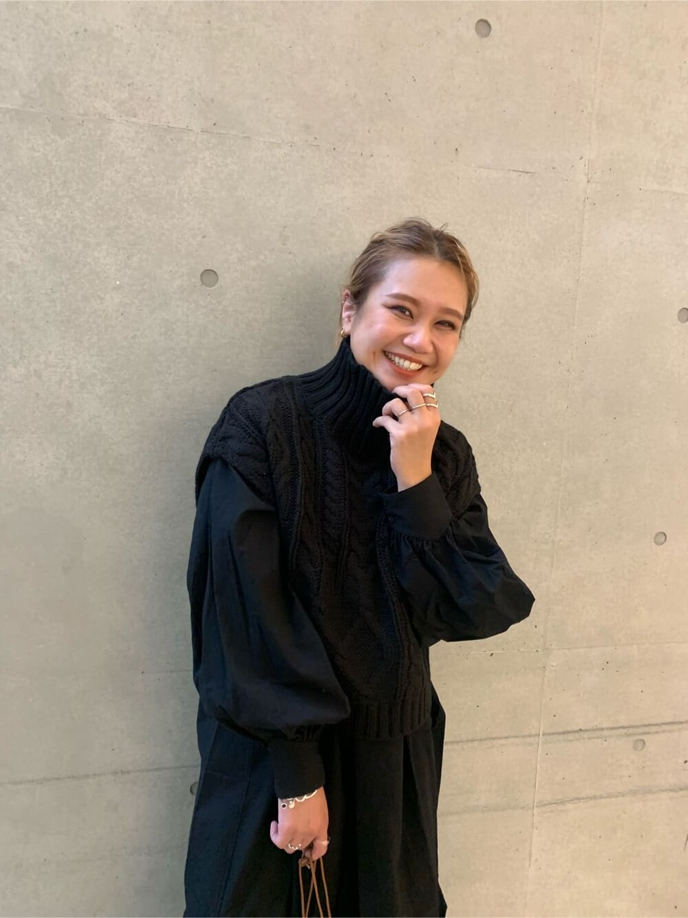 ブルー系のデニムパンツ、ブラック系のワンピース、イエロー系のハンドバッグを着用したレディースの秋コーディネートの2枚目の写真