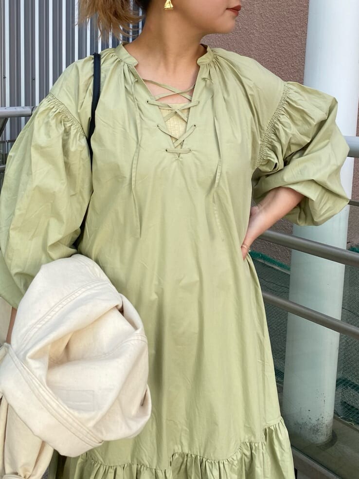 グリーン系のワンピース、ブラック系のショルダーバッグ、ホワイト系のデニムジャケットを着用したレディースの冬コーディネートの4枚目の写真