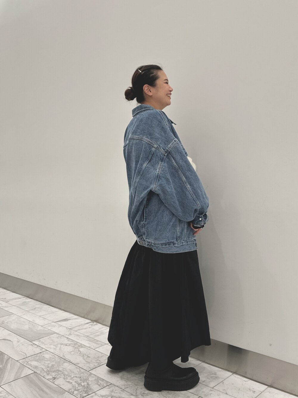 ブルー系のデニムジャケット、ブラック系のワンピース、ホワイト系のショルダーバッグを着用したレディースの秋コーディネートの2枚目の写真