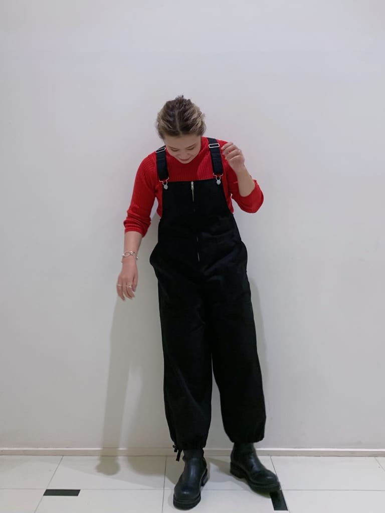 ブラック系のつなぎ/オールインワン、ブラック系のブーツ、レッド系のニット/セーターを着用したレディースの秋コーディネートの2枚目の写真