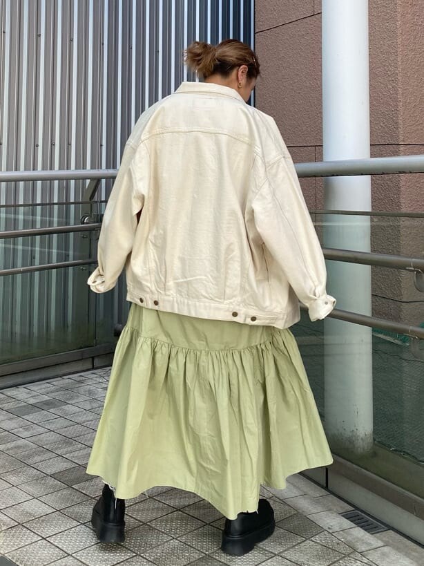 グリーン系のワンピース、ブラック系のショルダーバッグ、ホワイト系のデニムジャケットを着用したレディースの冬コーディネートの2枚目の写真