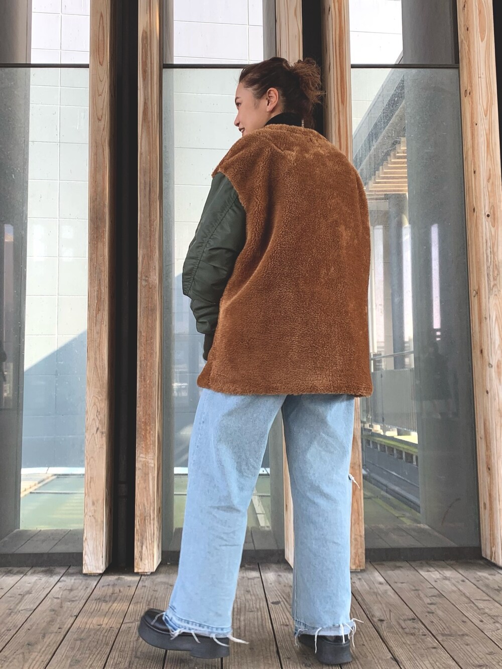 ブルー系のデニムパンツ、ブラック系のニット/セーター、グリーン系のブルゾンを着用したレディースの秋コーディネートの3枚目の写真