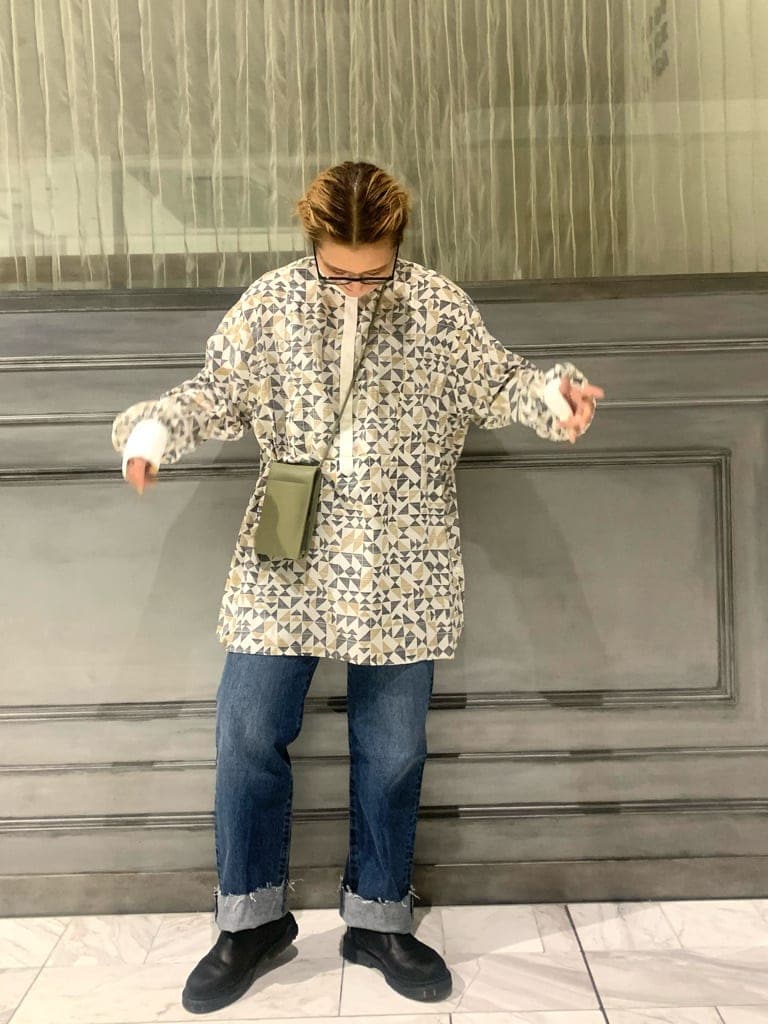 ホワイト系のポンチョ、ブラウン系のシャツ/ブラウス、ブルー系のデニムパンツを着用したレディースの秋コーディネートの3枚目の写真