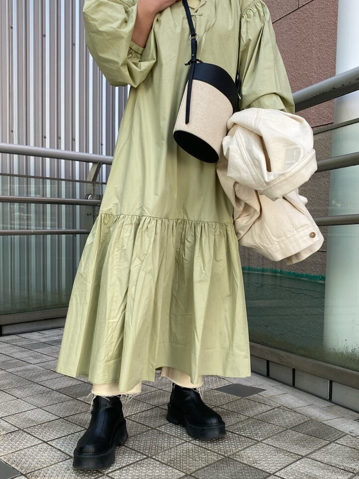 グリーン系のワンピース、ブラック系のショルダーバッグ、ホワイト系のデニムジャケットを着用したレディースの冬コーディネートの5枚目の写真