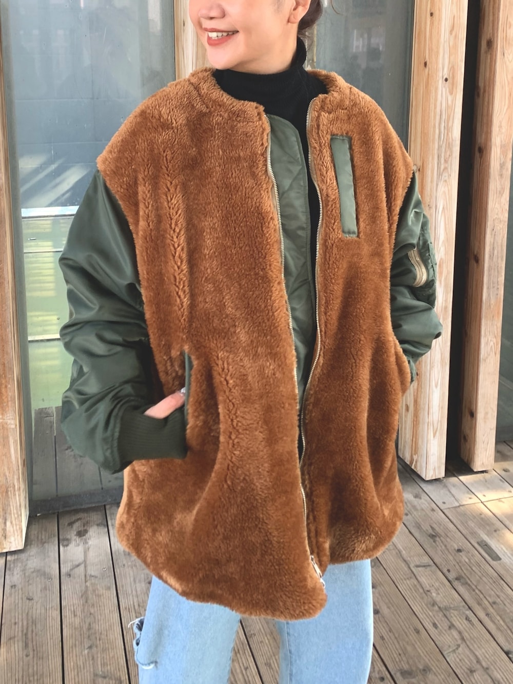 ブルー系のデニムパンツ、ブラック系のニット/セーター、グリーン系のブルゾンを着用したレディースの秋コーディネートの5枚目の写真