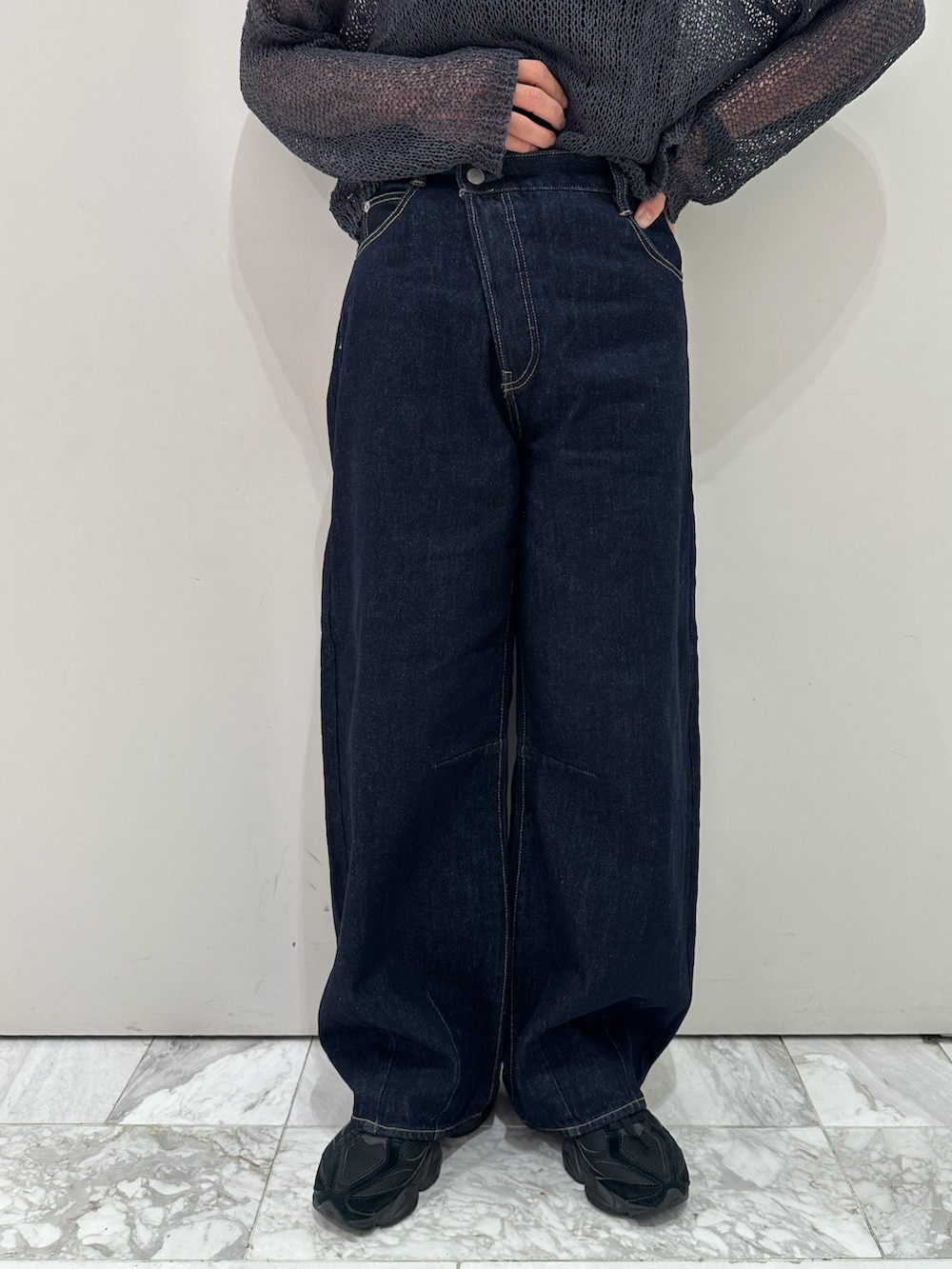 グレー系のニット/セーター、ブラック系のキャミソール、ブルー系のデニムパンツを着用したレディースの秋コーディネートの6枚目の写真