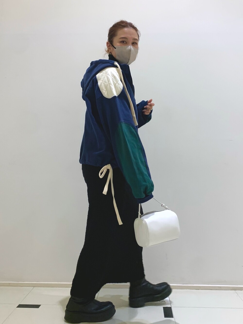 ブルー系のパーカー、ブラック系のスカート、ブラック系のハンドバッグを着用したレディースの冬コーディネートの3枚目の写真