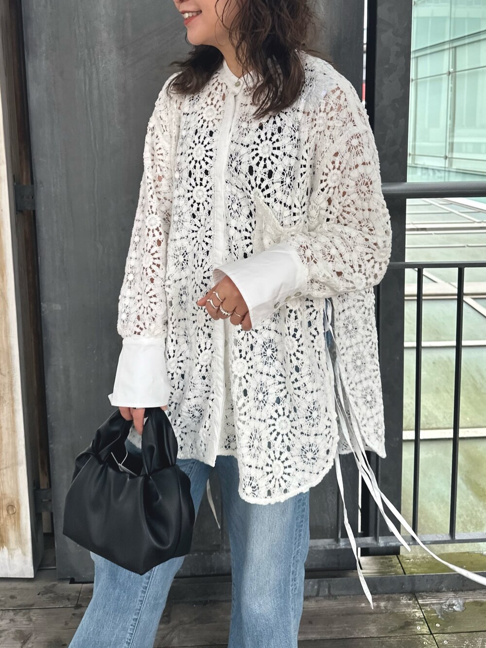 ホワイト系のシャツ/ブラウス、ブラック系のハンドバッグ、ブルー系のデニムパンツを着用したレディースの春コーディネートの3枚目の写真