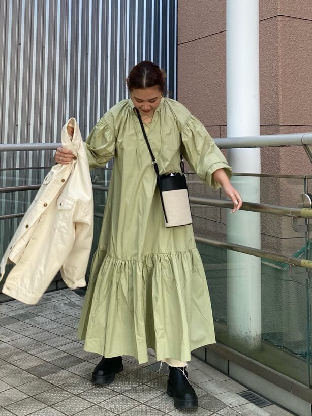 グリーン系のワンピース、ブラック系のショルダーバッグ、ホワイト系のデニムジャケットを着用したレディースの冬コーディネートの3枚目の写真