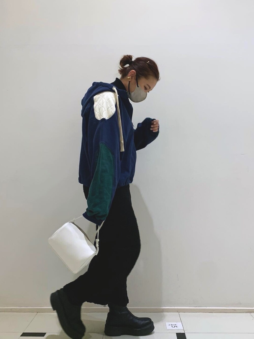 ブルー系のパーカー、ブラック系のスカート、ブラック系のハンドバッグを着用したレディースの冬コーディネートの2枚目の写真