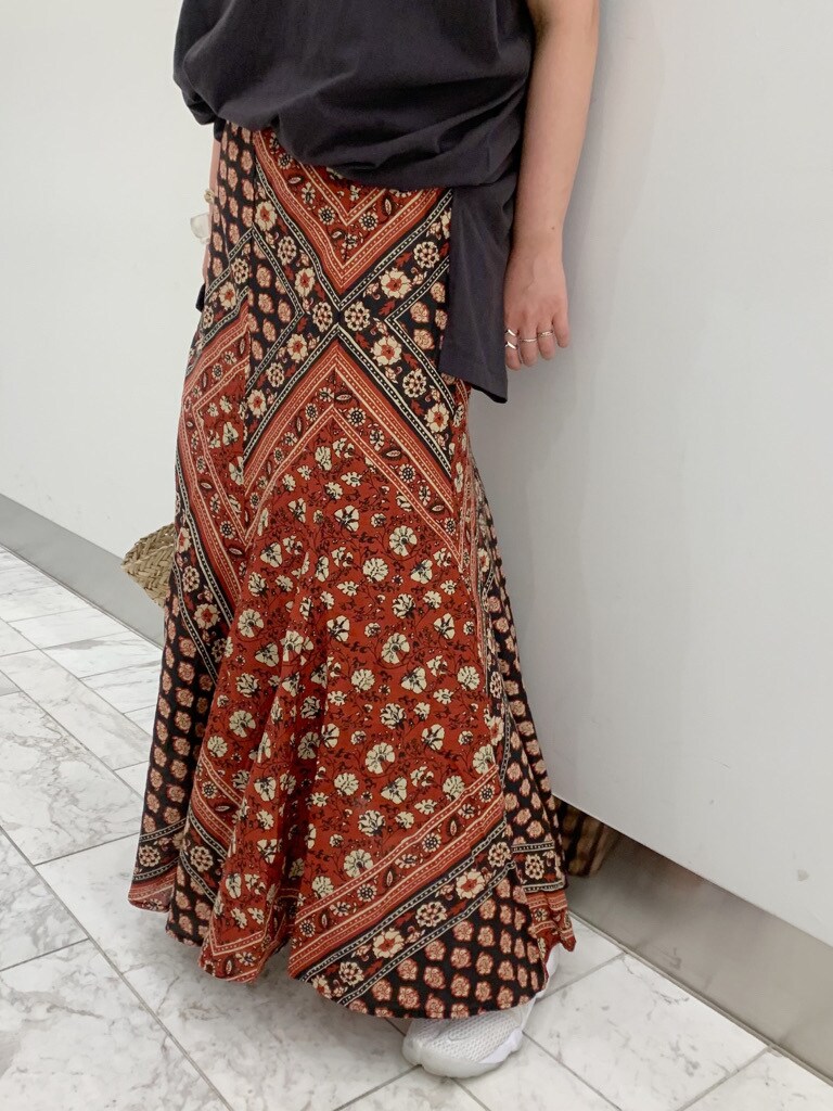 ベージュ系のかごバッグ、レッド系のスカート、グレー系のTシャツ/カットソーを着用したレディースの夏コーディネートの4枚目の写真