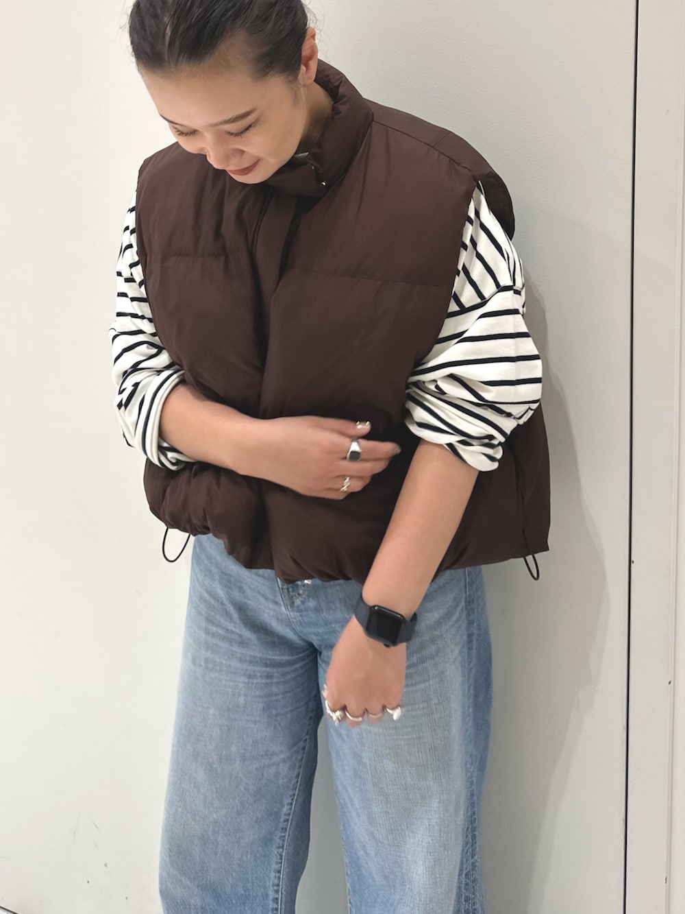 ブルー系のデニムパンツ、ブルー系のTシャツ/カットソー、ブラウン系のダウンベストを着用したレディースの秋コーディネートの4枚目の写真