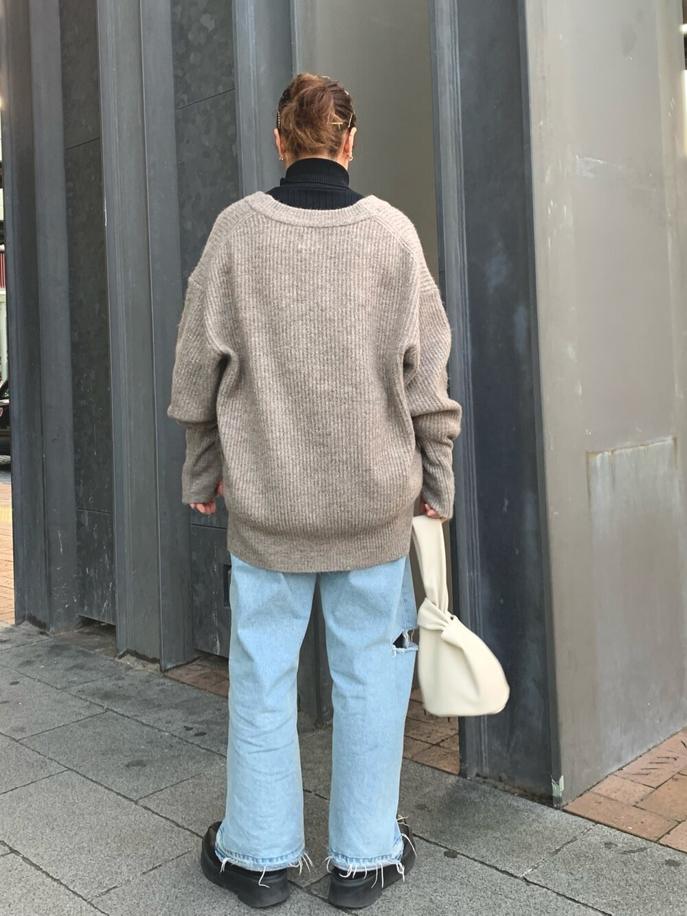 ホワイト系のハンドバッグ、グレー系のカーディガン/ボレロ、ブラック系のニット/セーターを着用したレディースの冬コーディネートの3枚目の写真