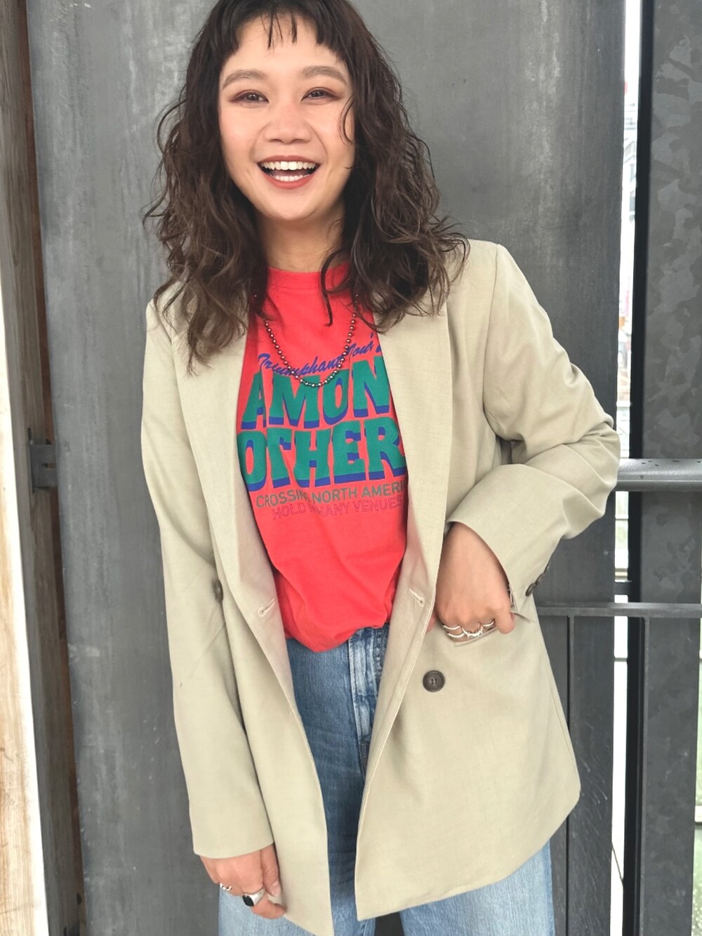 オレンジ系のTシャツ/カットソー、ブルー系のデニムパンツ、ベージュ系のテーラードジャケットを着用したレディースの春コーディネートの2枚目の写真