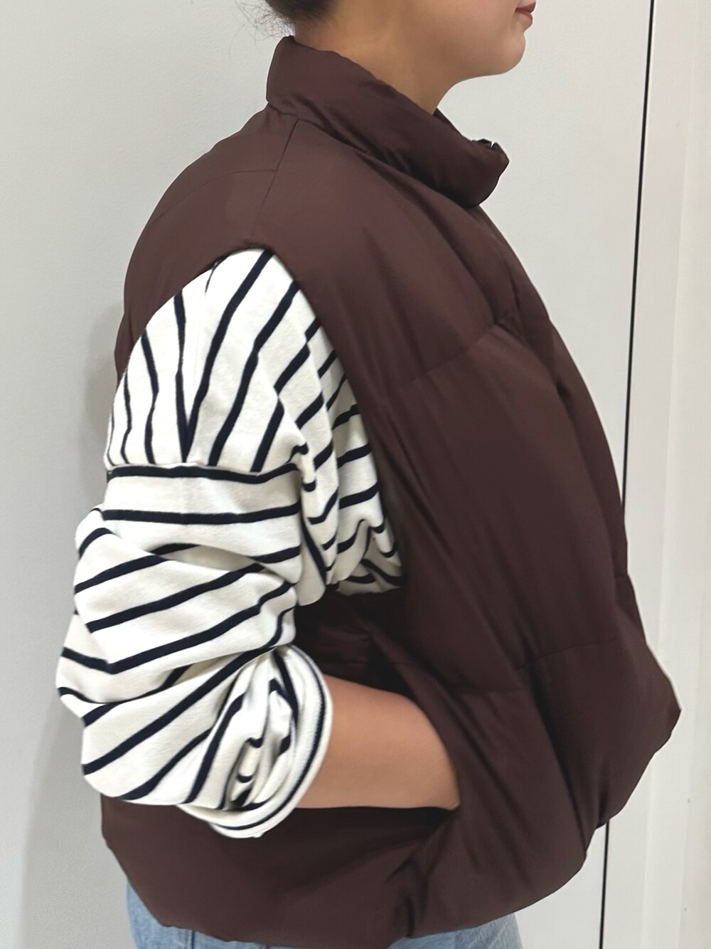 ブルー系のデニムパンツ、ブルー系のTシャツ/カットソー、ブラウン系のダウンベストを着用したレディースの秋コーディネートの5枚目の写真