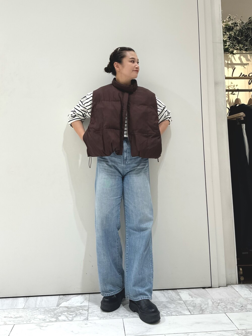 ブルー系のデニムパンツ、ブルー系のTシャツ/カットソー、ブラウン系のダウンベストを着用したレディースの秋コーディネートの2枚目の写真