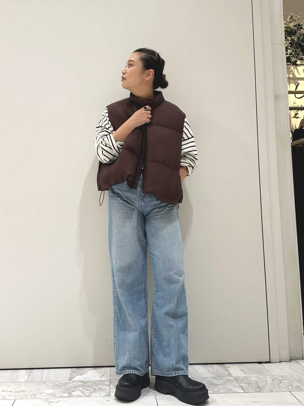 ブルー系のデニムパンツ、ブルー系のTシャツ/カットソー、ブラウン系のダウンベストを着用したレディースの秋コーディネートの3枚目の写真