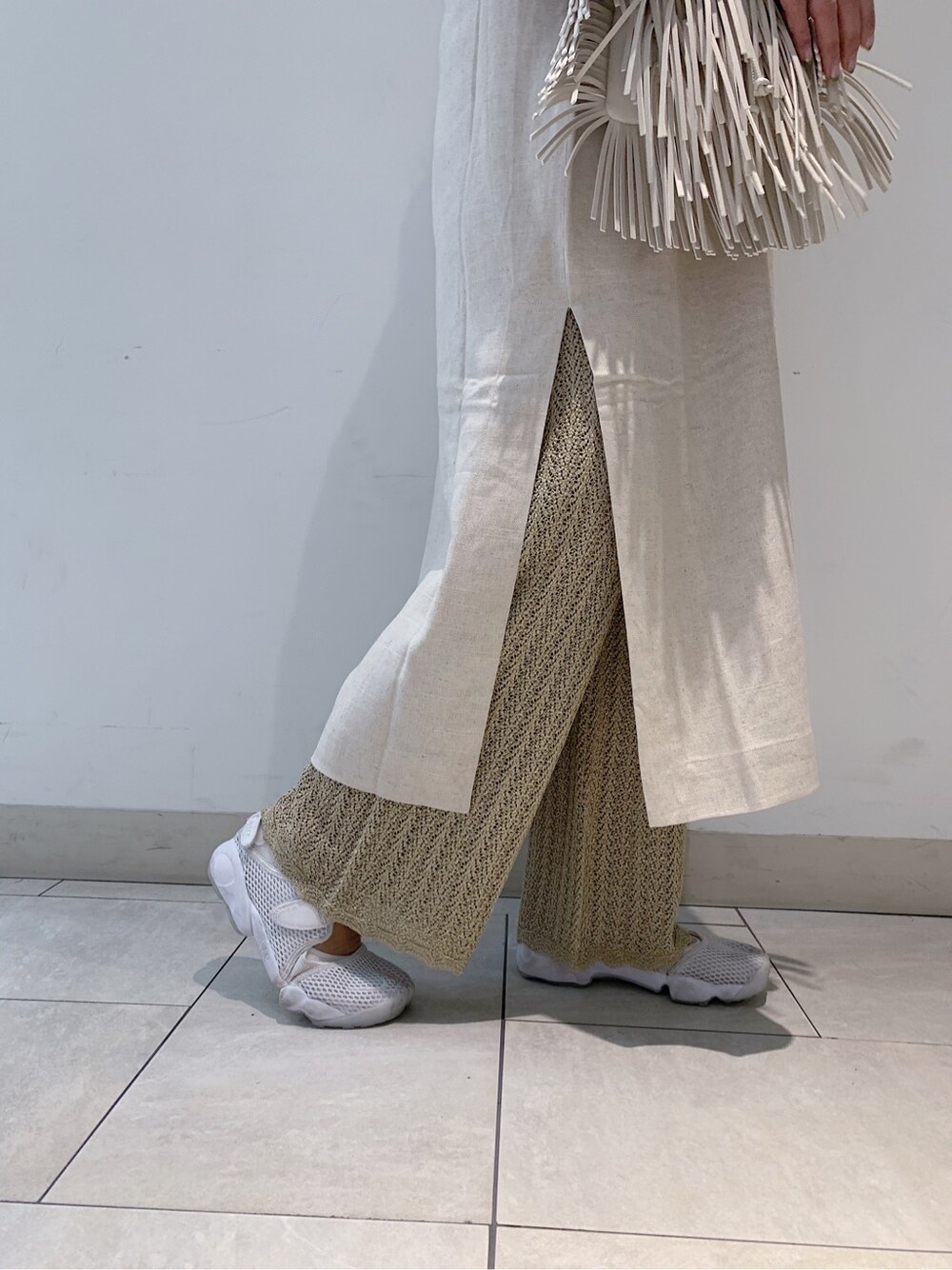 ホワイト系のハンドバッグ、ホワイト系のワンピース、ゴールド系のその他パンツを着用したレディースの春コーディネートの3枚目の写真