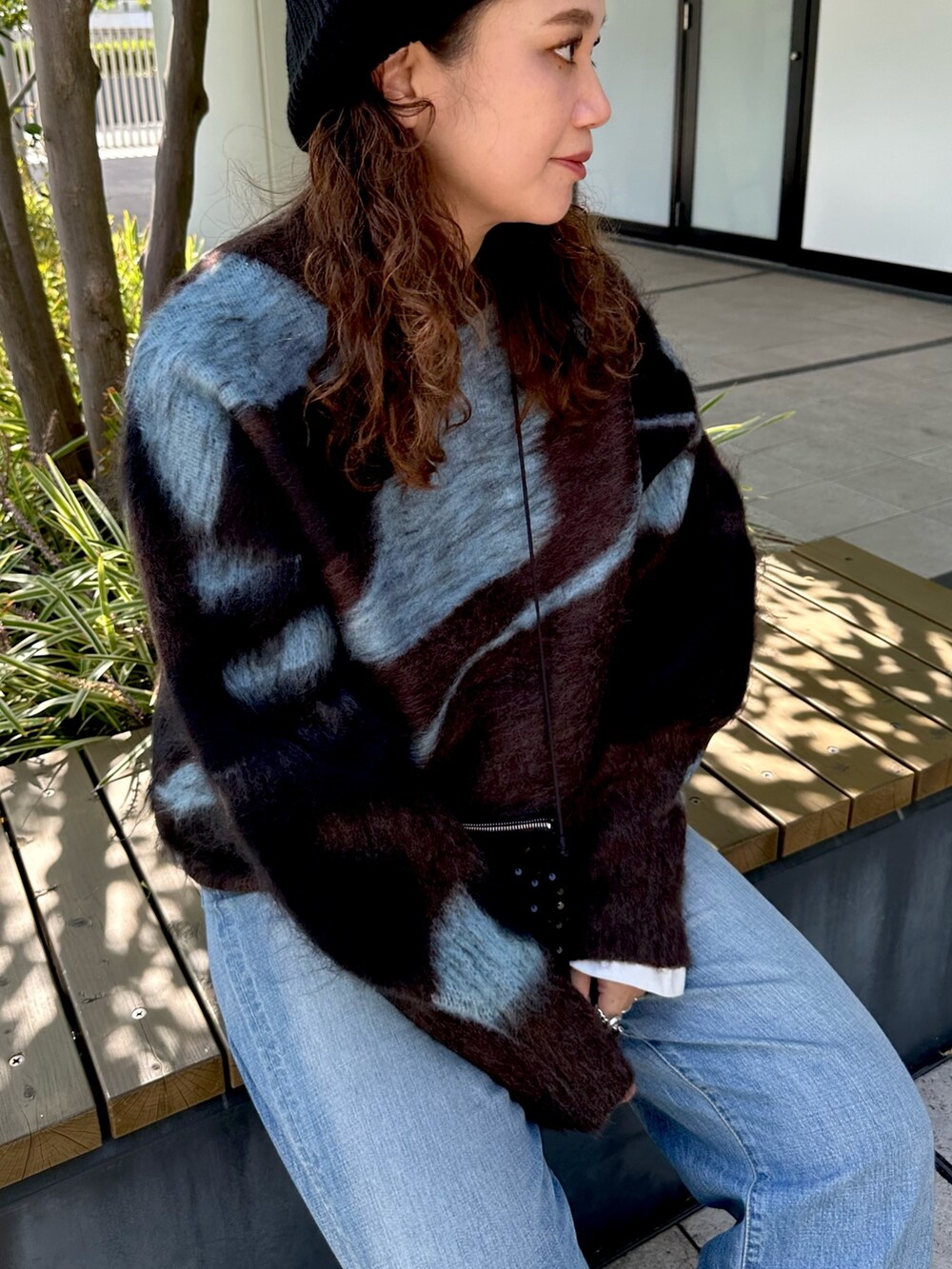 ブラウン系のニット/セーター、ブラック系のショルダーバッグ、ブルー系のデニムパンツを着用したレディースの秋コーディネートの3枚目の写真