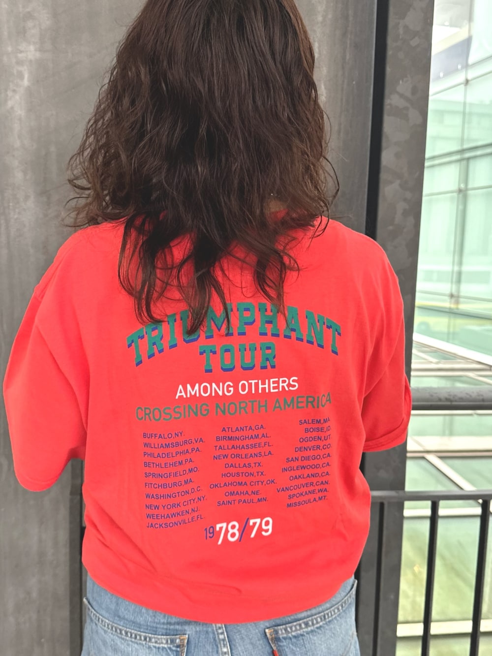 オレンジ系のTシャツ/カットソー、ブルー系のデニムパンツ、ベージュ系のテーラードジャケットを着用したレディースの春コーディネートの4枚目の写真