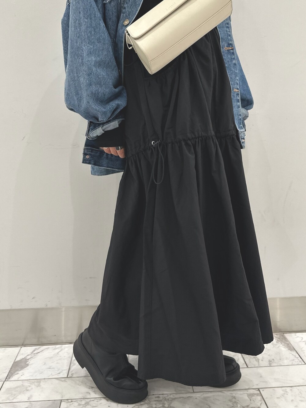 ブルー系のデニムジャケット、ブラック系のワンピース、ホワイト系のショルダーバッグを着用したレディースの秋コーディネートの5枚目の写真