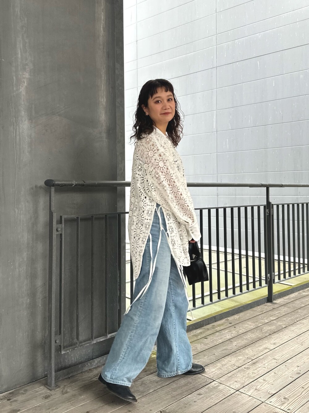 ホワイト系のシャツ/ブラウス、ブラック系のハンドバッグ、ブルー系のデニムパンツを着用したレディースの春コーディネートの2枚目の写真