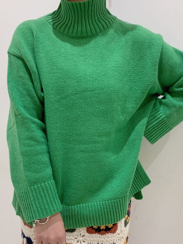 ホワイト系のスカート、ブラック系のブーツ、グリーン系のニット/セーターを着用したレディースの秋コーディネートの2枚目の写真