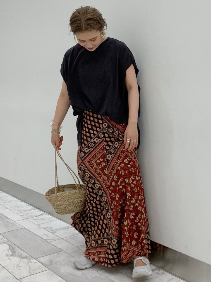 ベージュ系のかごバッグ、レッド系のスカート、グレー系のTシャツ/カットソーを着用したレディースの夏コーディネートの2枚目の写真