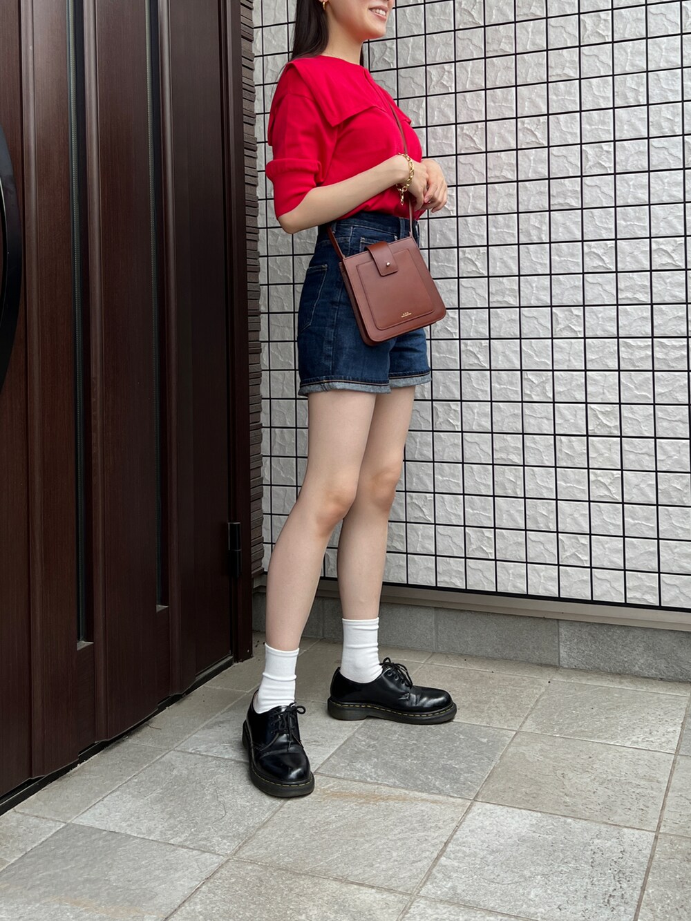 レッド系のニット/セーター、ブルー系のデニムパンツ、ブラウン系のショルダーバッグを着用したレディースの夏コーディネートの3枚目の写真