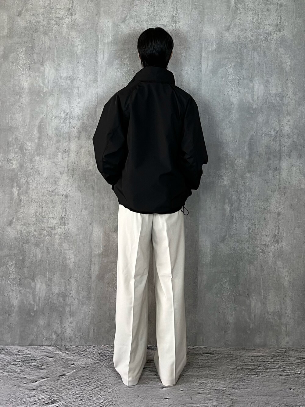 ホワイト系のスニーカー、ホワイト系のスラックス、ブラック系のブルゾンを着用したメンズの冬コーディネートの5枚目の写真